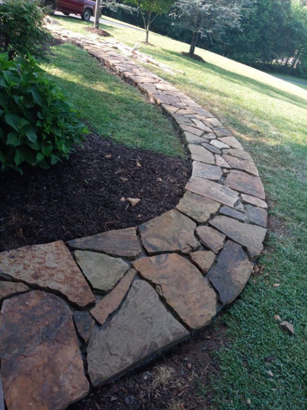 A stone walkway is going through a lush green field.
