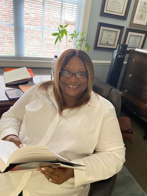 A woman is sitting in a chair reading a book.