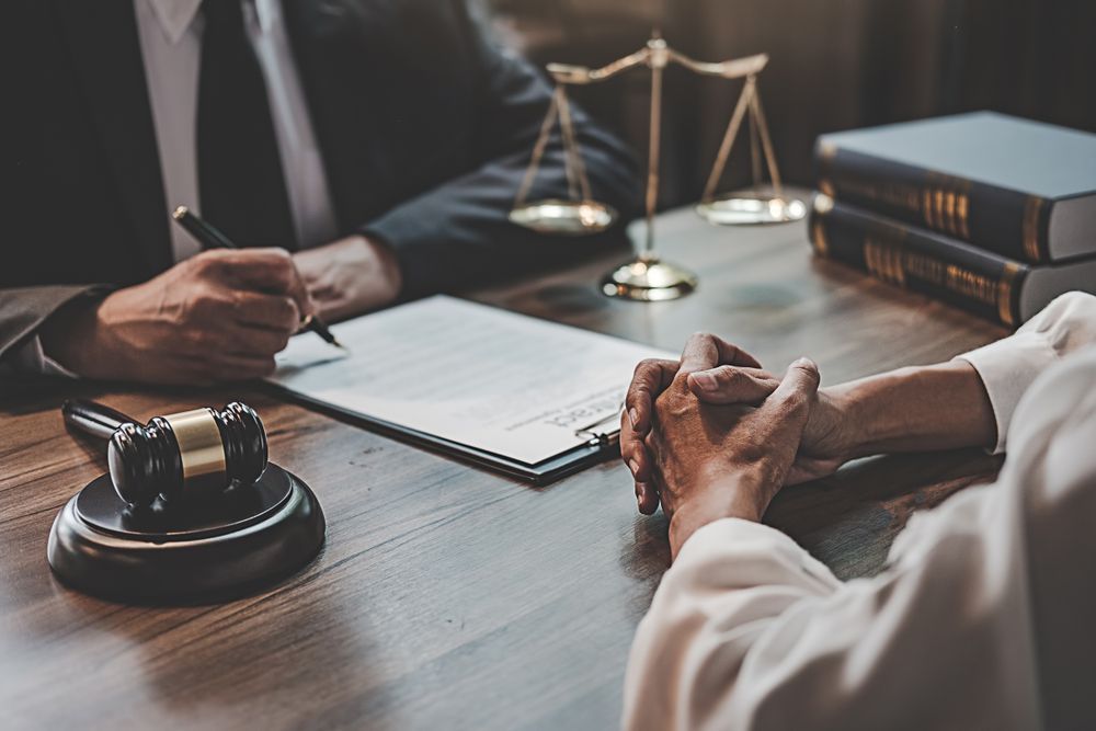 Two People Are Sitting at a Table With a Gavel and Scales of Justice — ACT Law Associates In Canberra, ACT