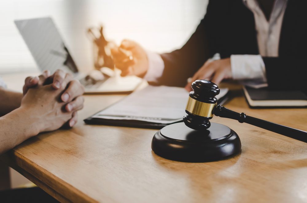 A Judge's Gavel is on a Wooden Table Next to a Person Sitting at a Desk — ACT Law Associates In Canberra, ACT