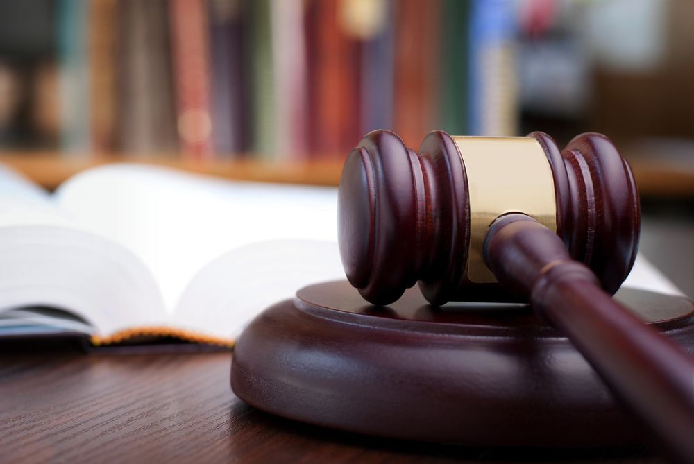 A Wooden Judge's Gavel is Sitting on a Wooden Table Next to an Open Book — ACT Law Associates In Tuggeranong, ACT