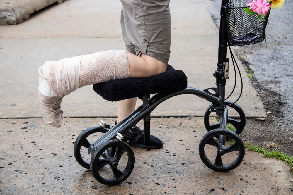 A Person With a Cast on Their Leg is Sitting on a Knee Walker — ACT Law Associates In Tuggeranong, ACT