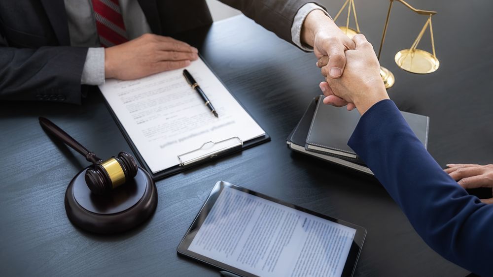 A Lawyer and a Client Are Shaking Hands at a Table — ACT Law Associates In Gungahlin, ACT