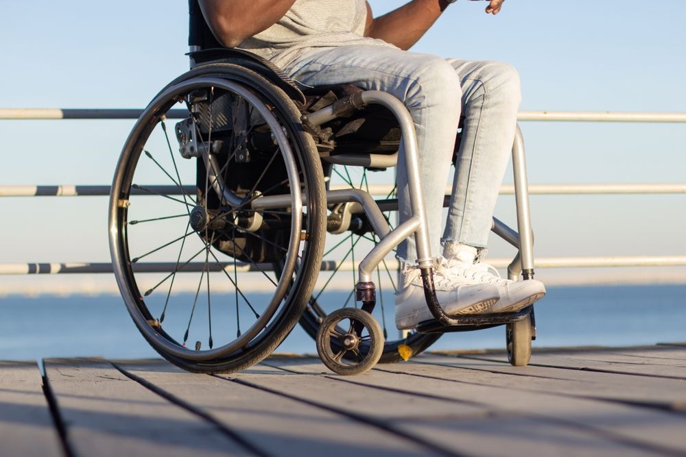 A Man in a Wheelchair is Sitting on a Pier — ACT Law Associates In Belconnen, ACT