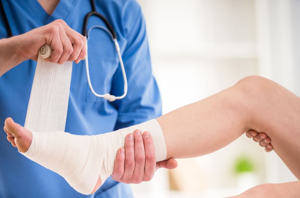 A Doctor is Bandaging a Patient's Ankle With a Bandage — ACT Law Associates In Tuggeranong, ACT