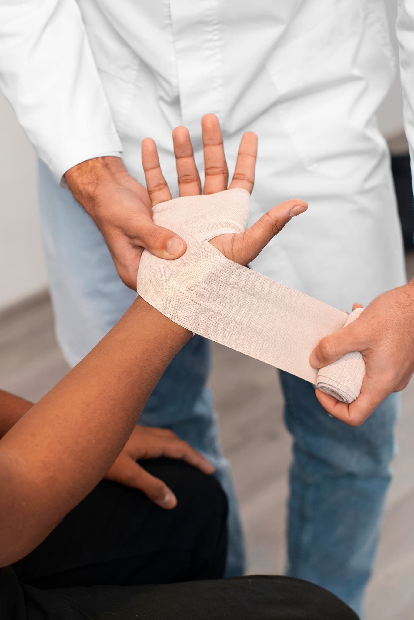 A Doctor is Wrapping a Patient's Wrist With a Bandage — ACT Law Associates In Woden, ACT