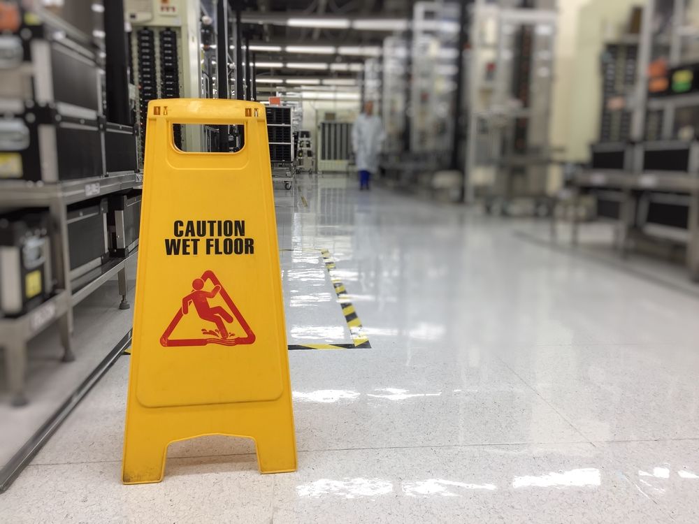 A Yellow Caution Wet Floor Sign is in a Warehouse — ACT Law Associates In Canberra, ACT
