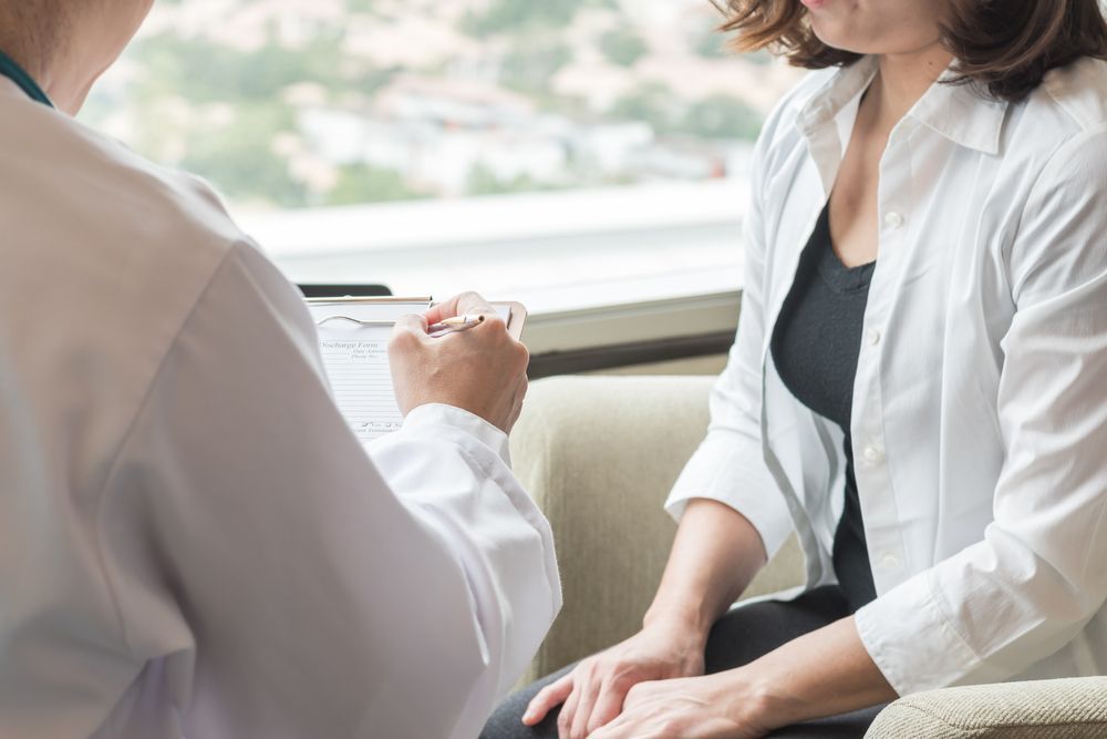 A Woman is Sitting on a Couch Talking to a Doctor — ACT Law Associates In Canberra, ACT