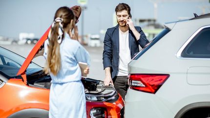 A Man is Talking on a Cell Phone While a Woman Stands Next to a Broken Down Car — ACT Law Associates In Canberra, ACT