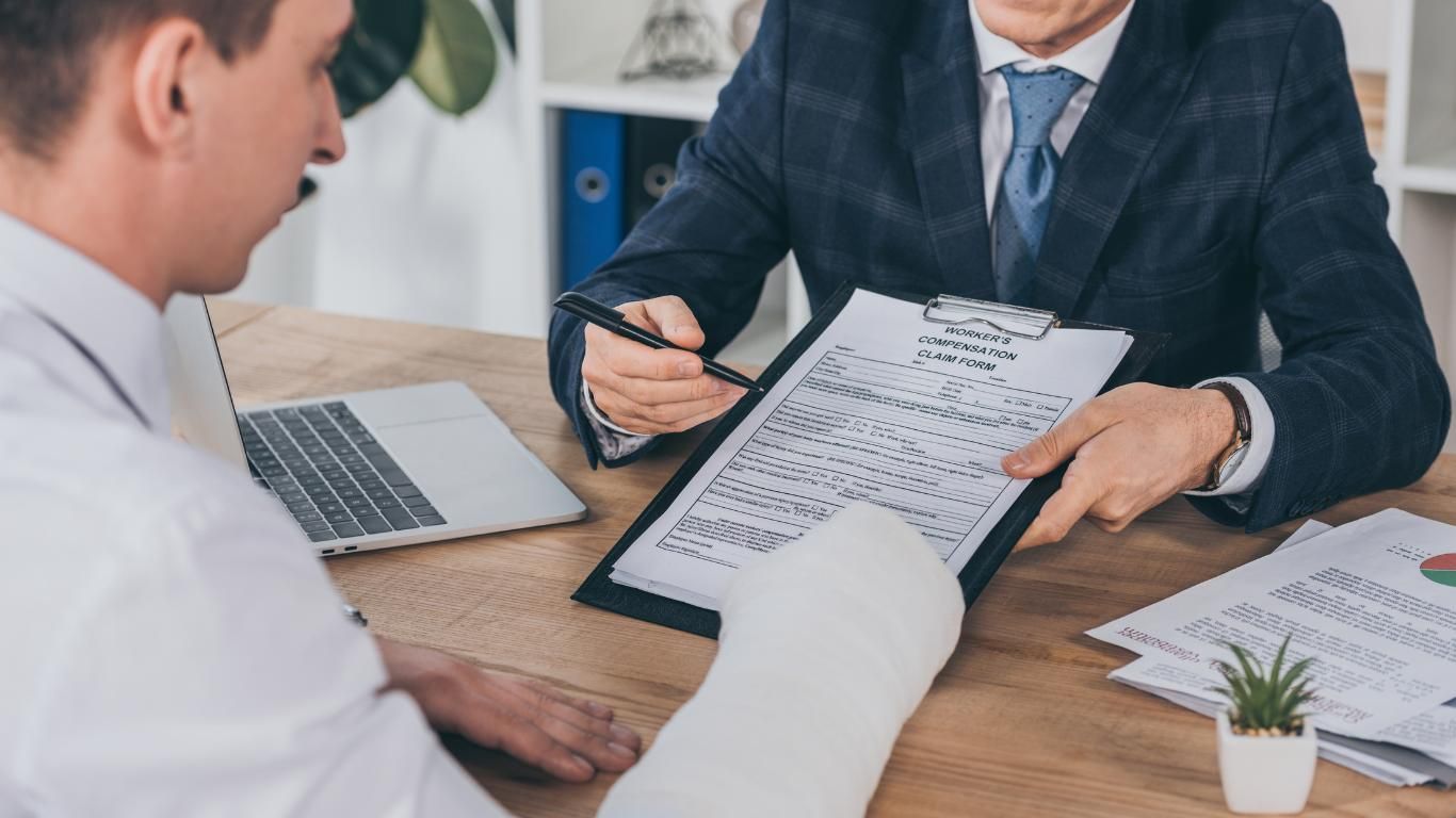Two Men Are Sitting at a Table Looking at a Clipboard — ACT Law Associates In Canberra, ACT