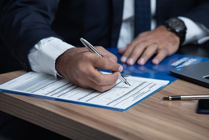 A Man is writing on a form — ACT Law Associates In Canberra, ACT