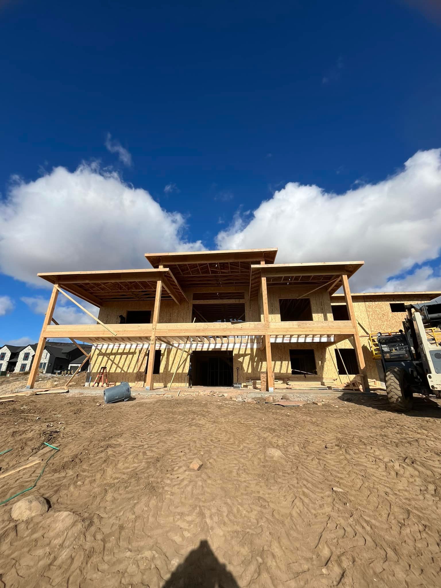 A large house is being built in the middle of a dirt field.