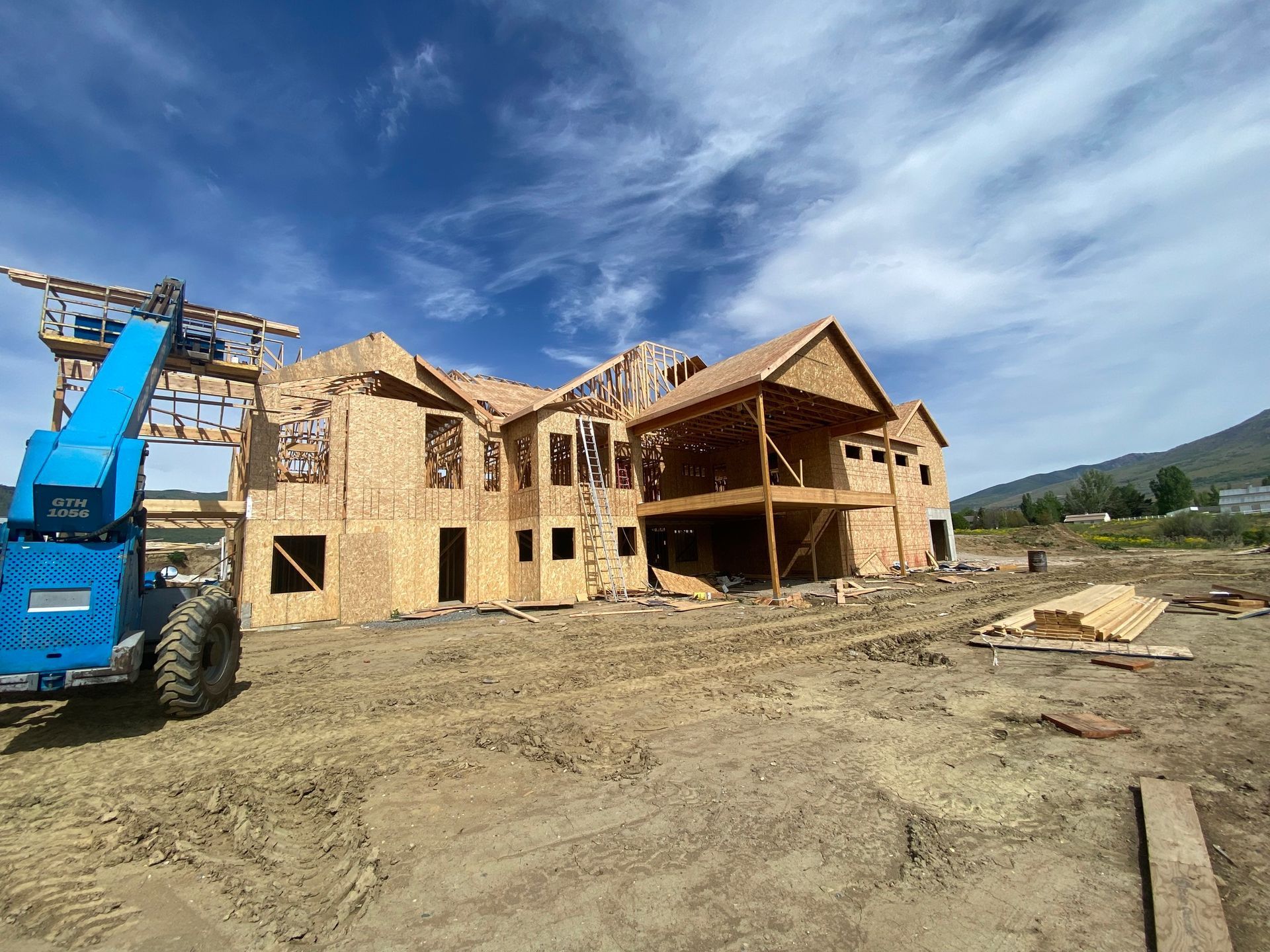 A large wooden house is being built in a dirt field.