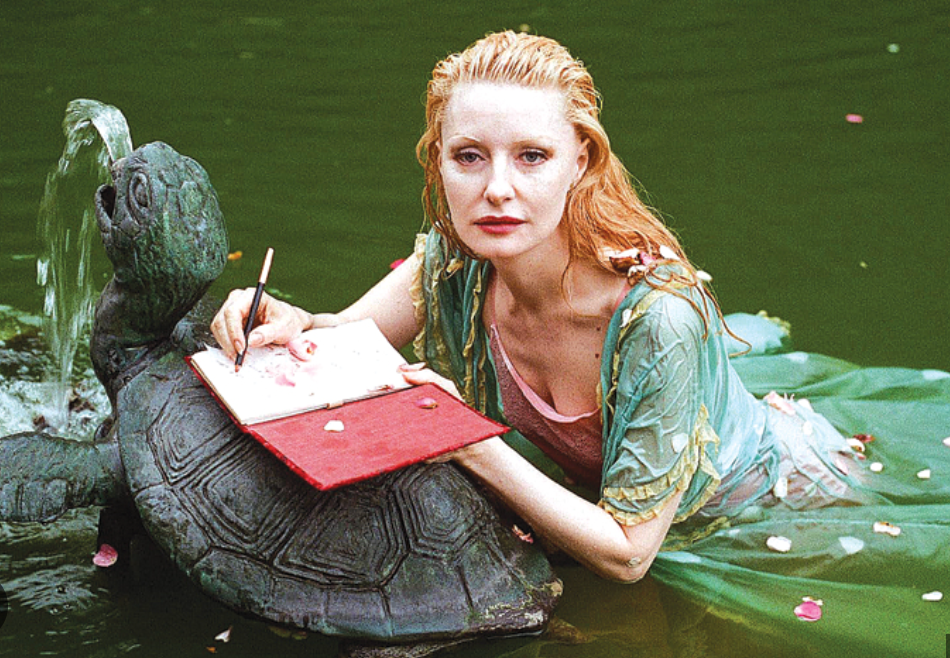 Photo of author and sex researcher Shere Hite lounging in water fountain with notebook and pen.