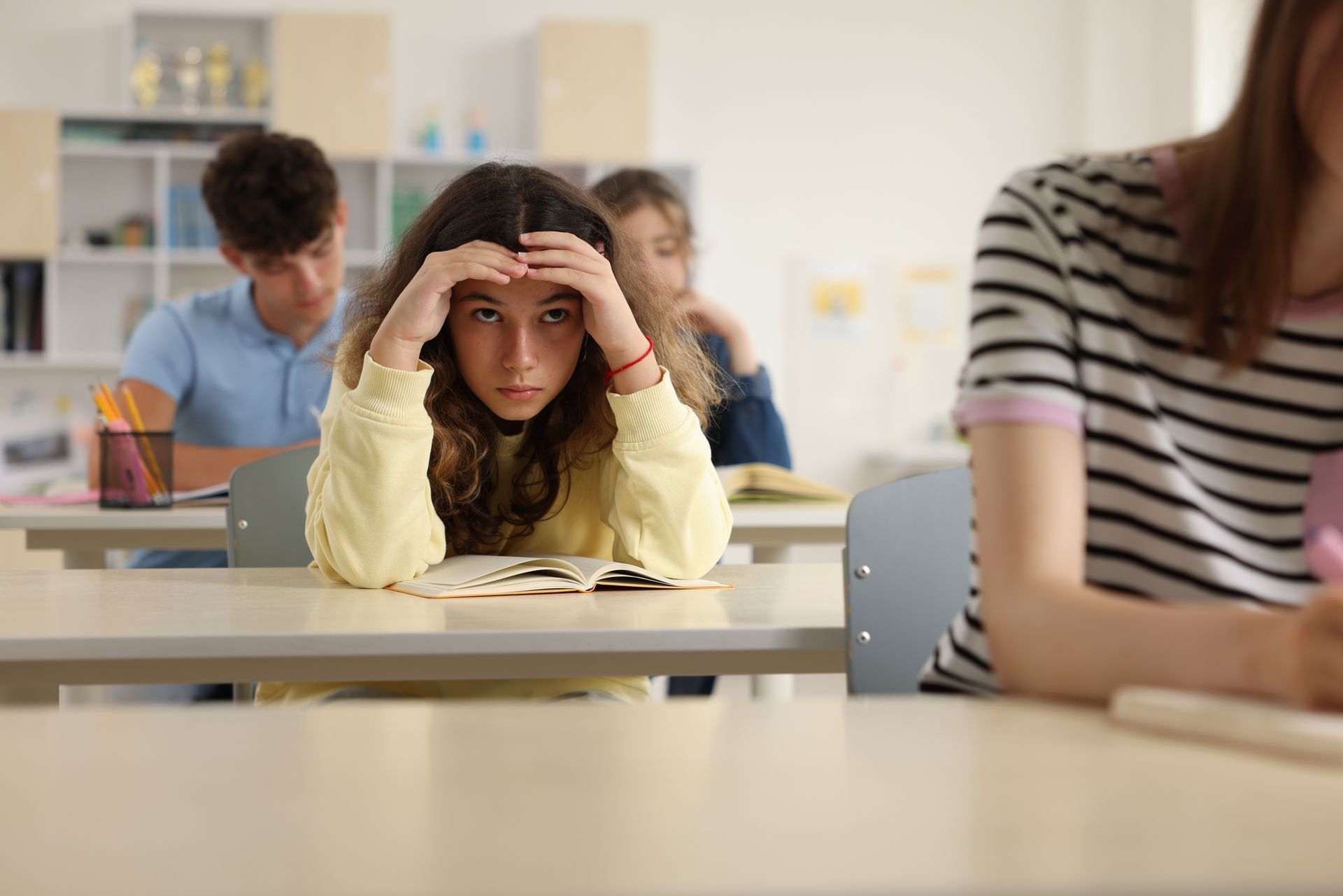 Girl in classroom looking unhappy and alienated.