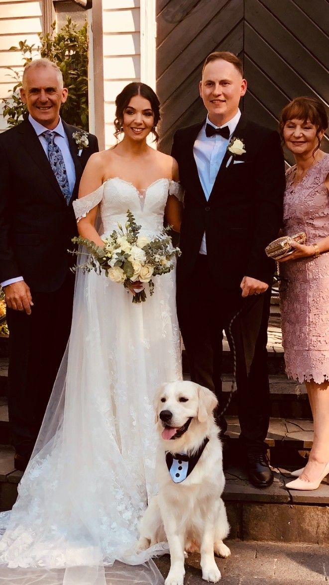 A Bride and Groom Are Posing for A Picture with Their Parents and A Do