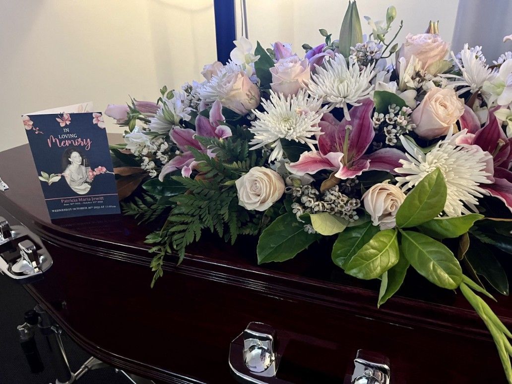 A Coffin with Flowers and A Card on It