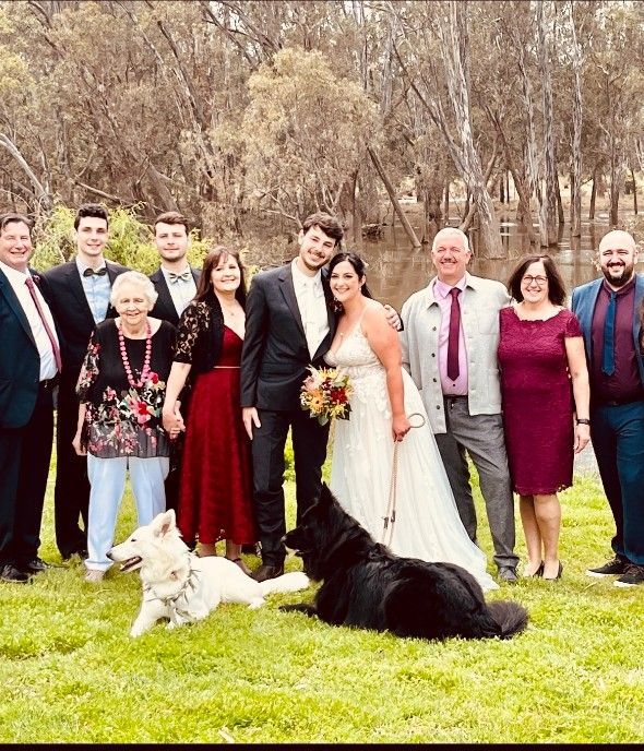 A Bride and Groom Are Posing for A Picture with Their Family and Their Dog
