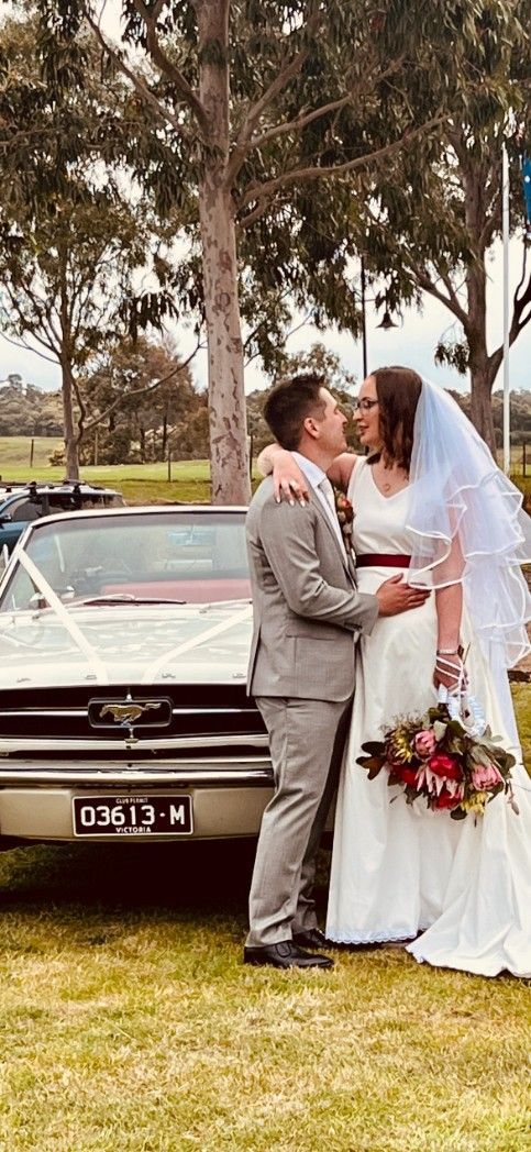 A Bride and Groom Are Kissing in Front of A Wedding Car