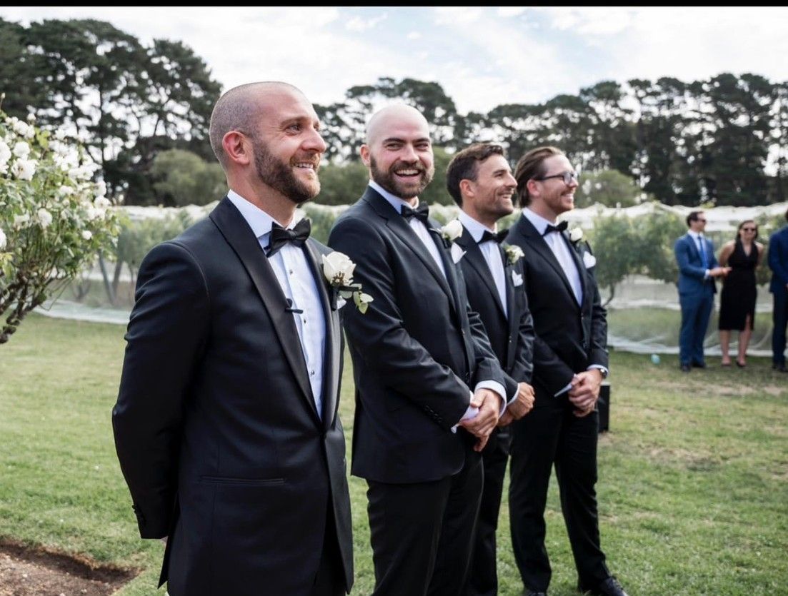 A Group of Men in Tuxedos Are Standing in The Grass