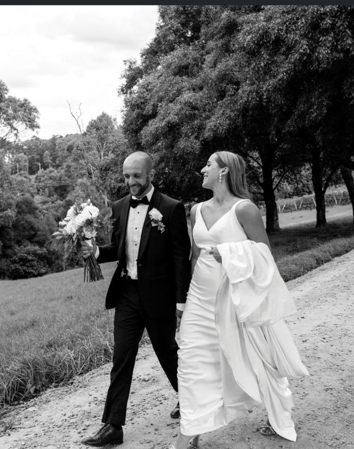 A Black and White Photo of A Bride and Groom Walking Down a Dirt Road