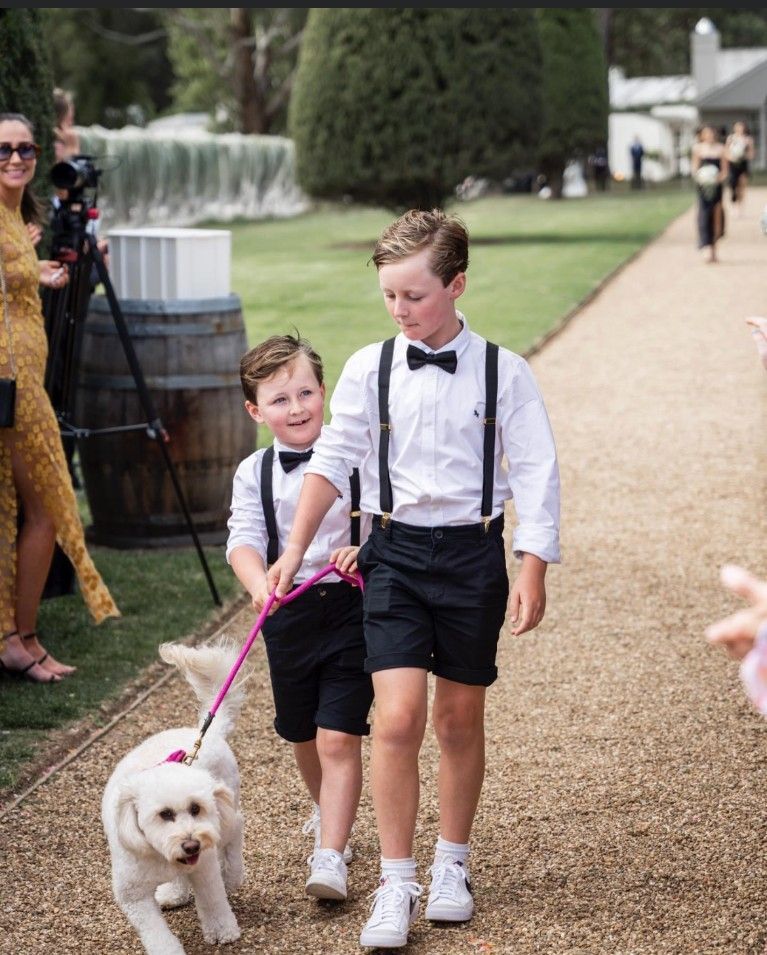Two Boys Are Walking a Small White Dog on A Leash
