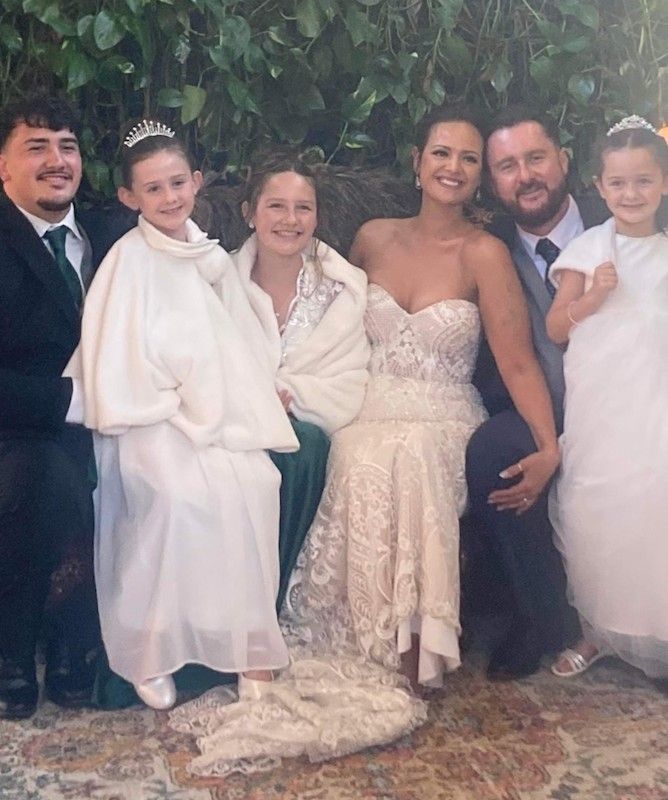 A Bride and Groom Are Posing for A Picture with Their Flower Girls