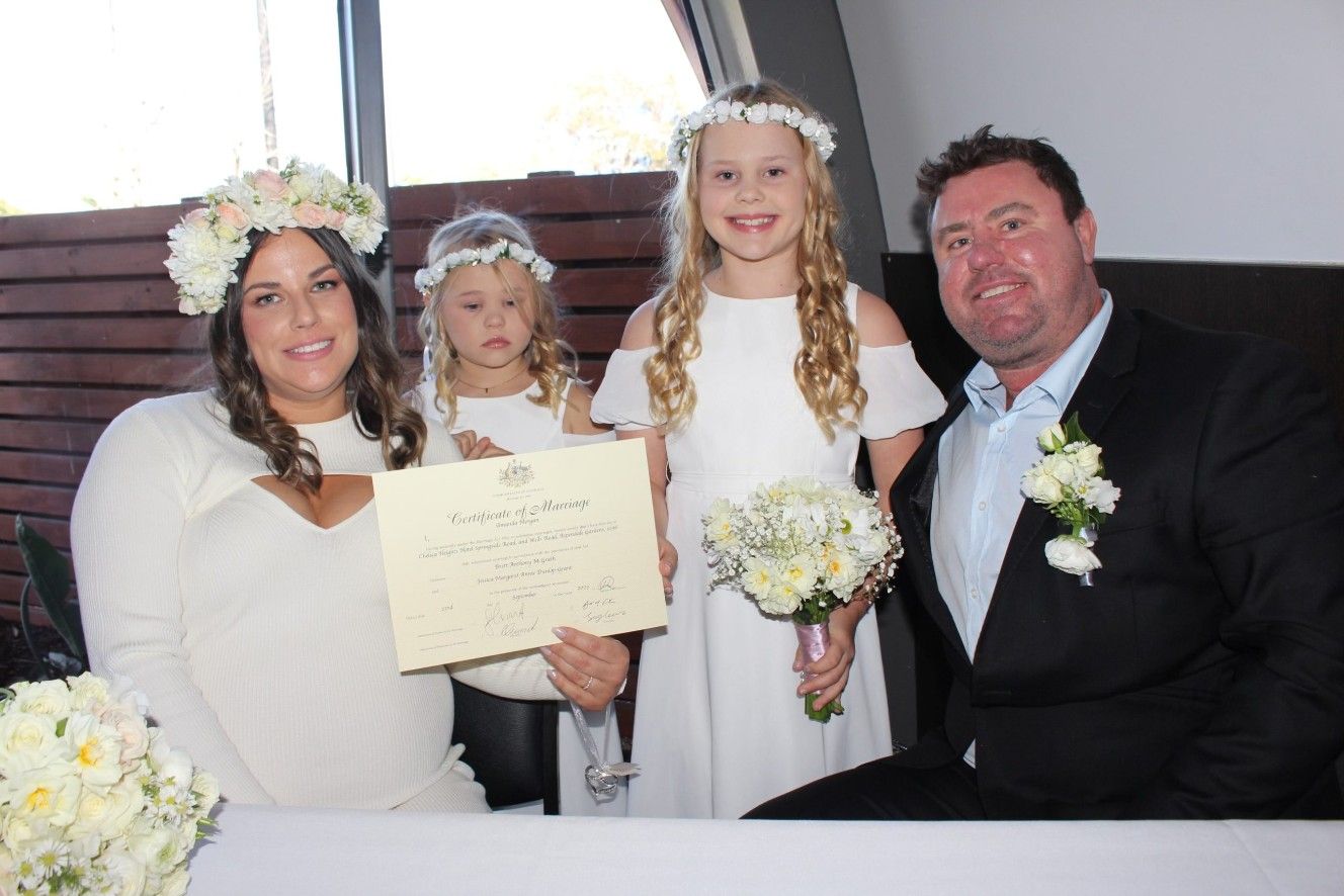 A Bride and Groom Are Posing for A Picture with Their Flower Girls