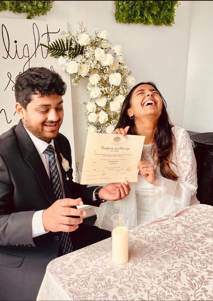 A Bride and Groom Are Sitting at A Table Holding a Wedding Certificate