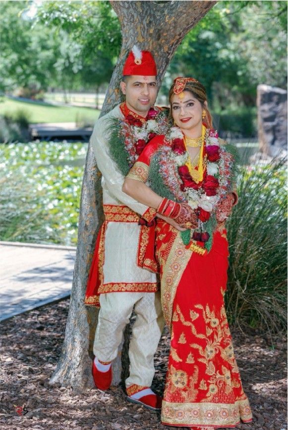 A Bride and Groom Are Posing for A Picture Next to A Tree