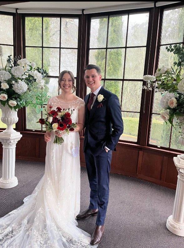 A Bride and Groom Are Posing for A Picture in Front of A Large Window