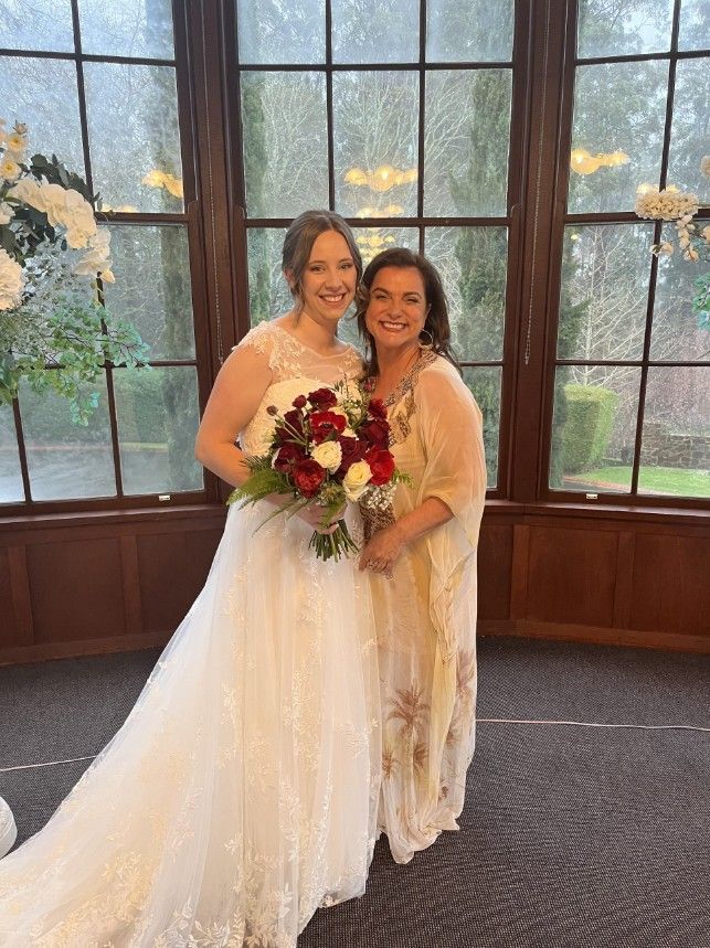 A Bride and Her Mother Are Posing for A Picture in Front of A Window
