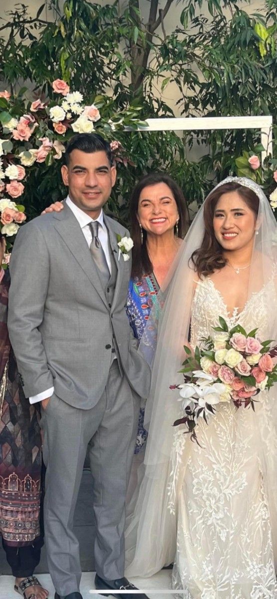 A Bride and Groom Are Posing for A Picture with Their Mother