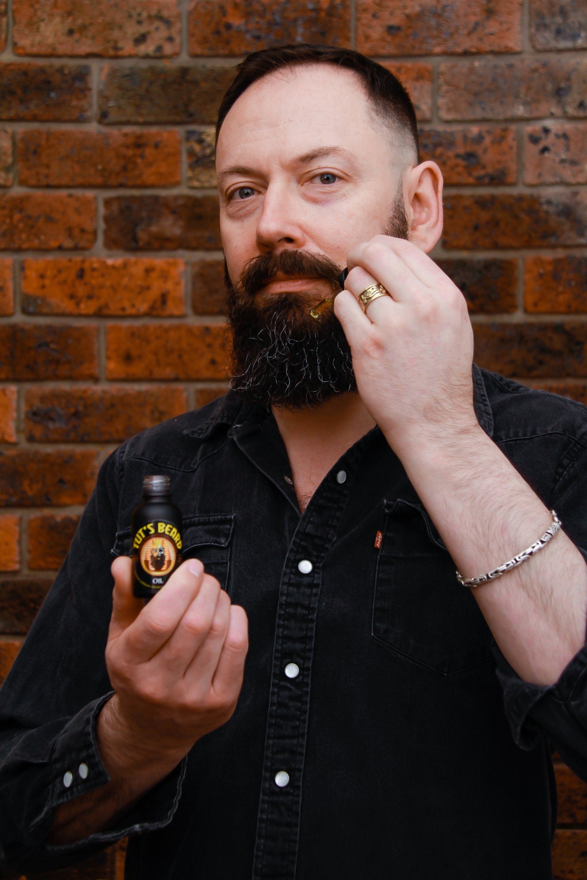 man pouring Tut's Beard oil on hand