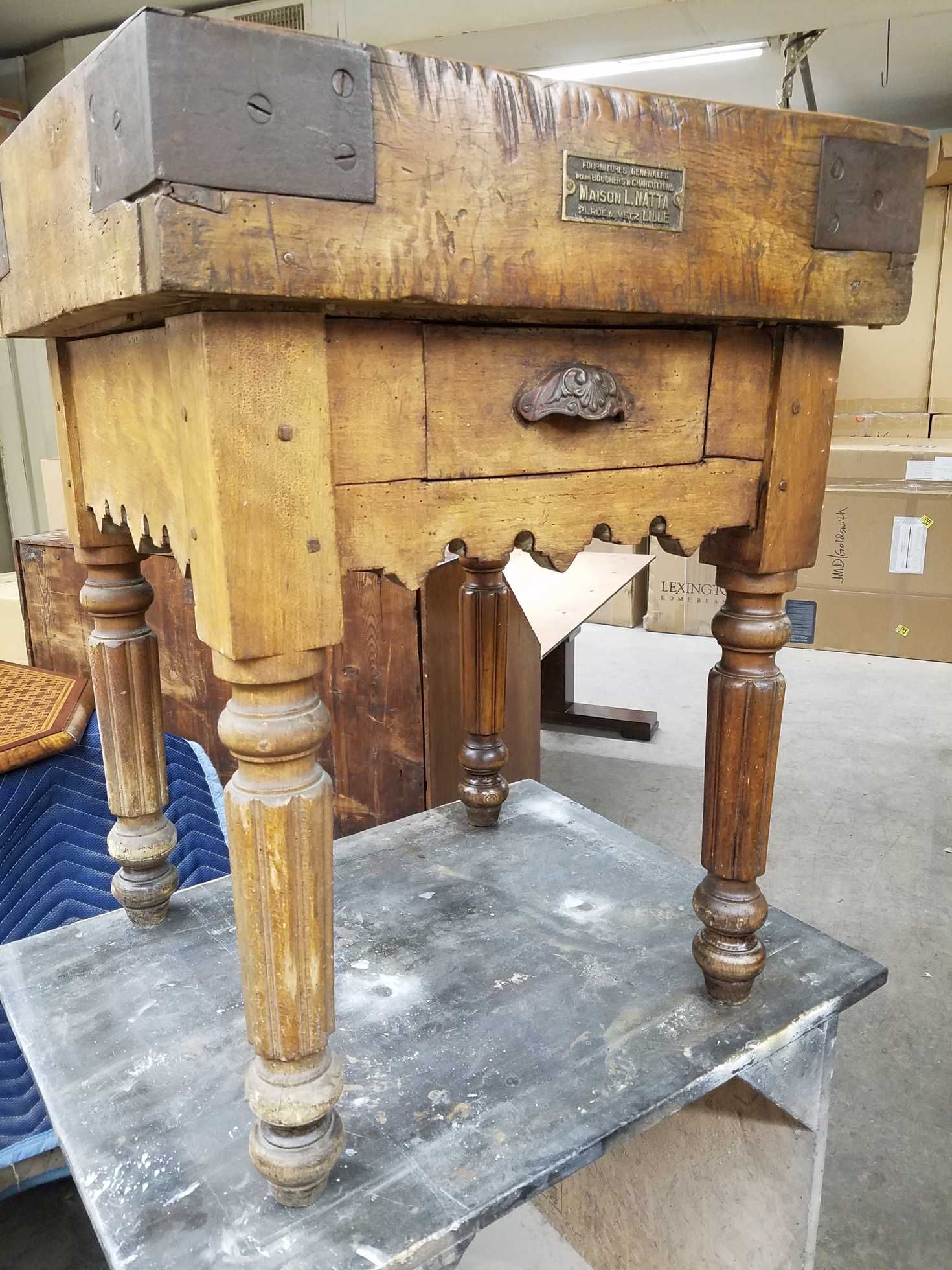 Antique wooden butcher block table with drawer and ornate legs.