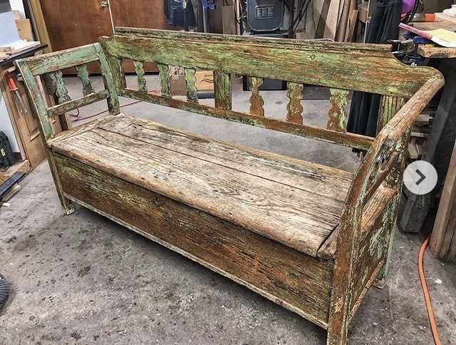 Weathered wooden bench with green paint, in a workshop.
