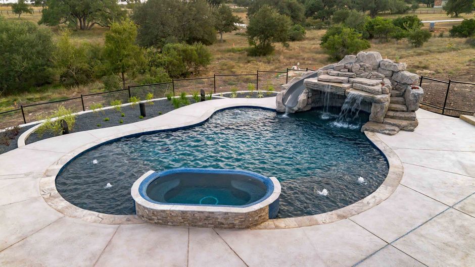 Pool with waterslide and attached spa in a natural setting New Braunfels