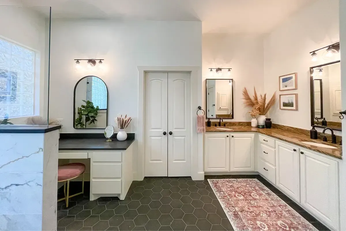 Spacious bathroom with white cabinets, vanity, black hexagon tiles, and decorative accents.