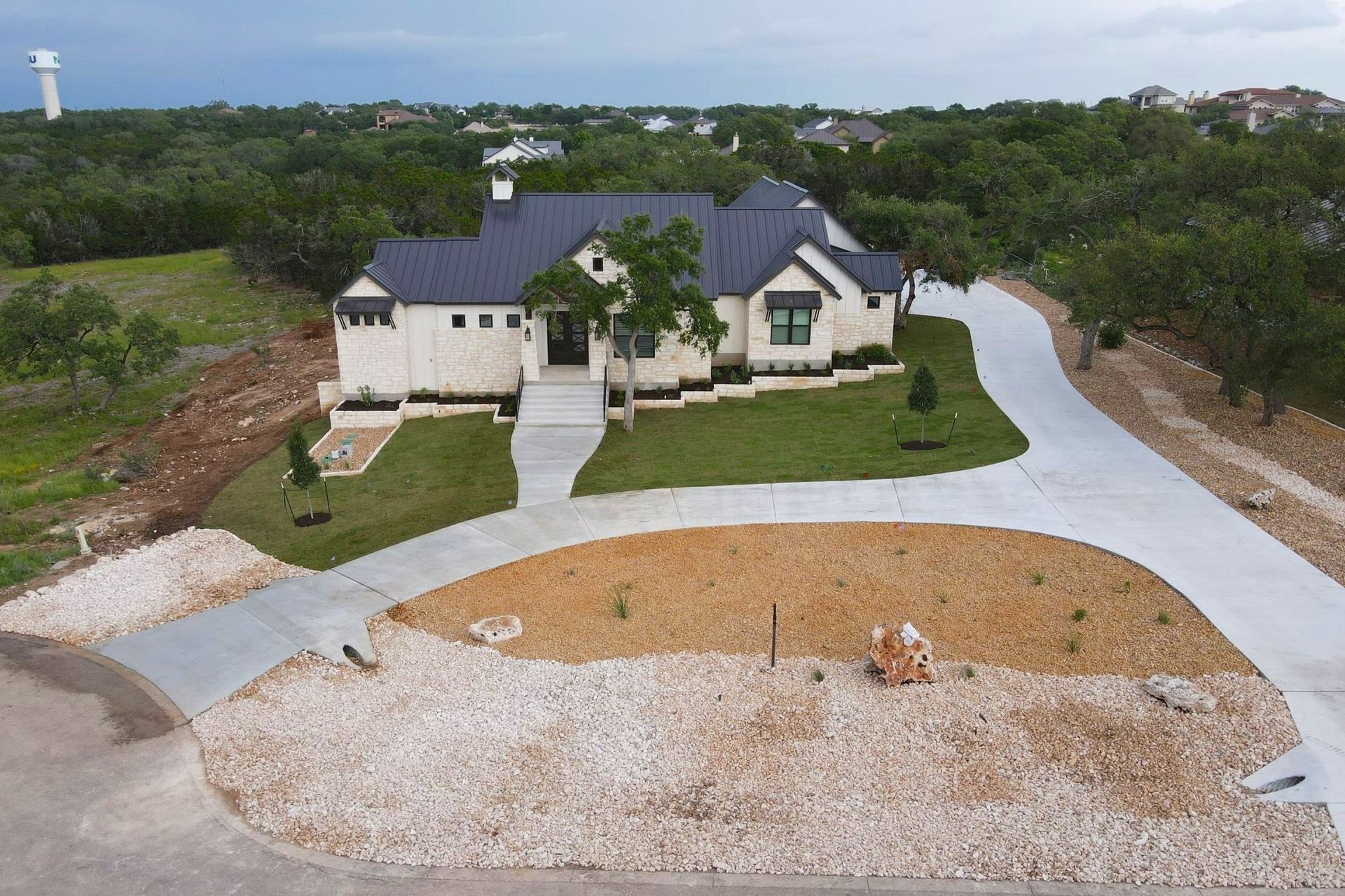 Pool with blue tiled interior, connected spa, and light-colored stone patio, under a cloudy sky.