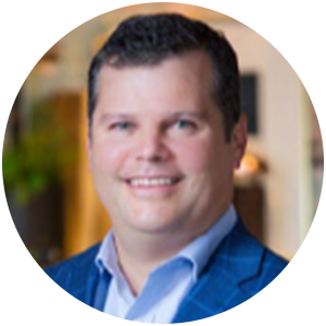 Man in a blue blazer smiles at the camera, indoors.