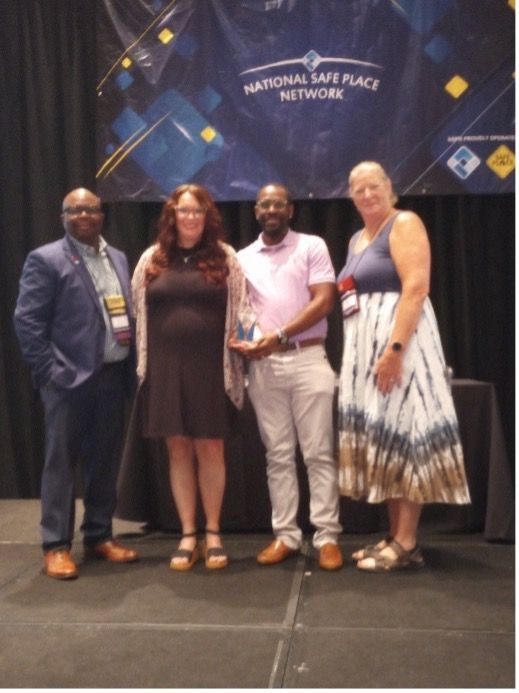Four people on a stage with a banner that says 