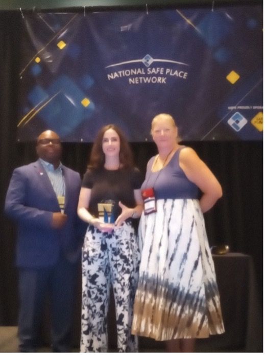 Three people on a stage with a banner reading 