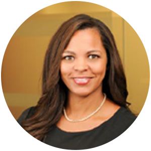 Woman with long brown hair, wearing a black top and a pearl necklace, smiling.