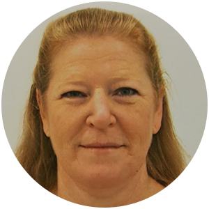 Woman with light brown hair in a round frame smiling slightly at the camera.