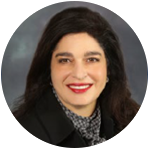 Woman with dark hair, wearing a black blazer and patterned scarf, smiling with red lipstick.