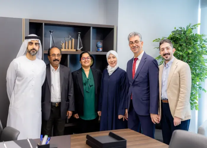 Six people in professional attire pose for a photo in an office setting.