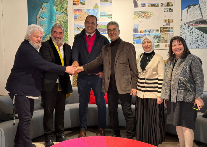 Group of six people shaking hands, smiling, in an office setting.