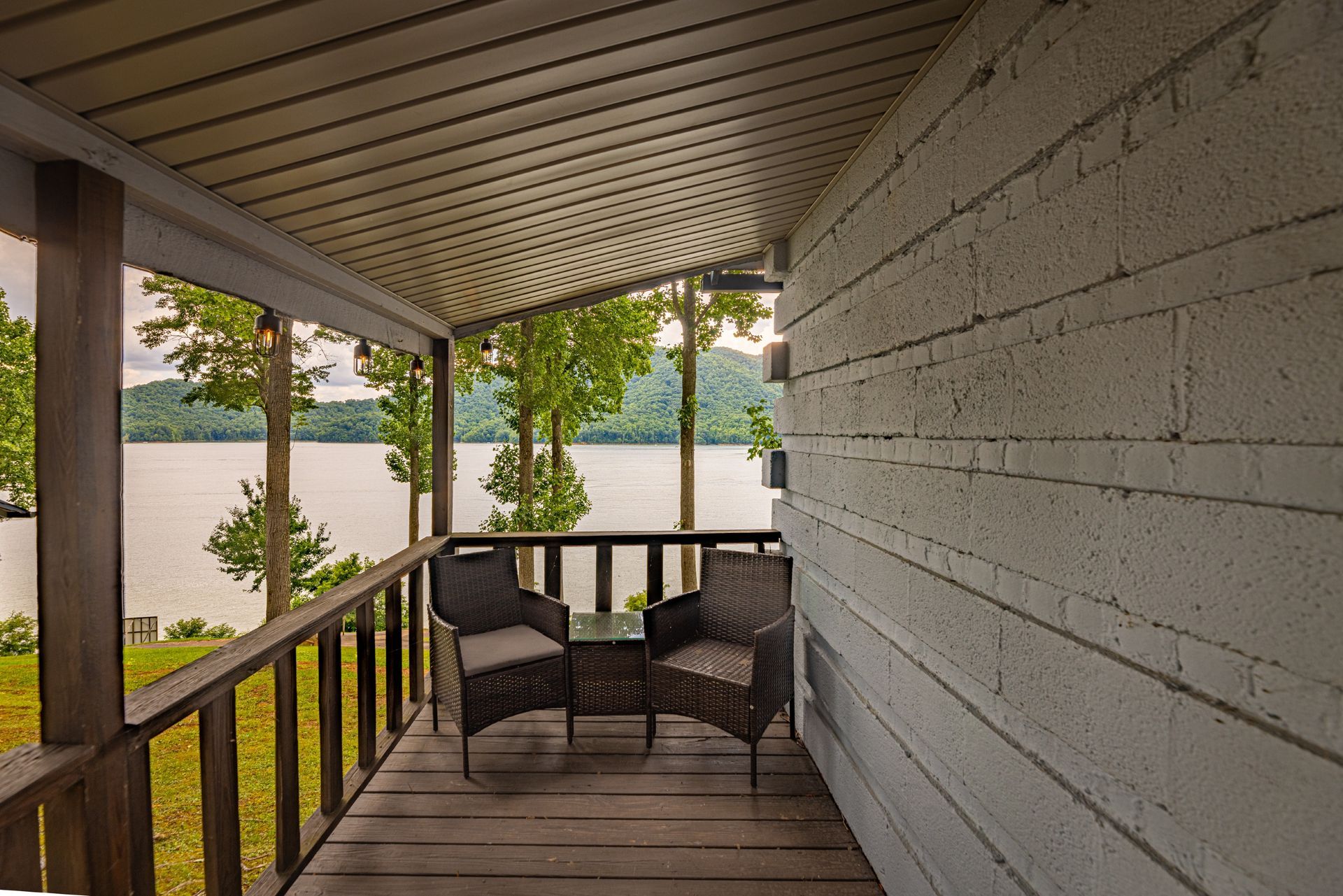 A porch with two chairs and a table overlooking a lake.