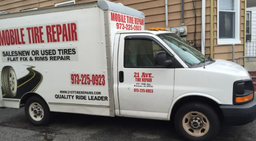 A mobile tire repair truck is parked in front of a house