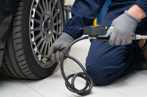 A man is kneeling down to inflate a tire with a pump.